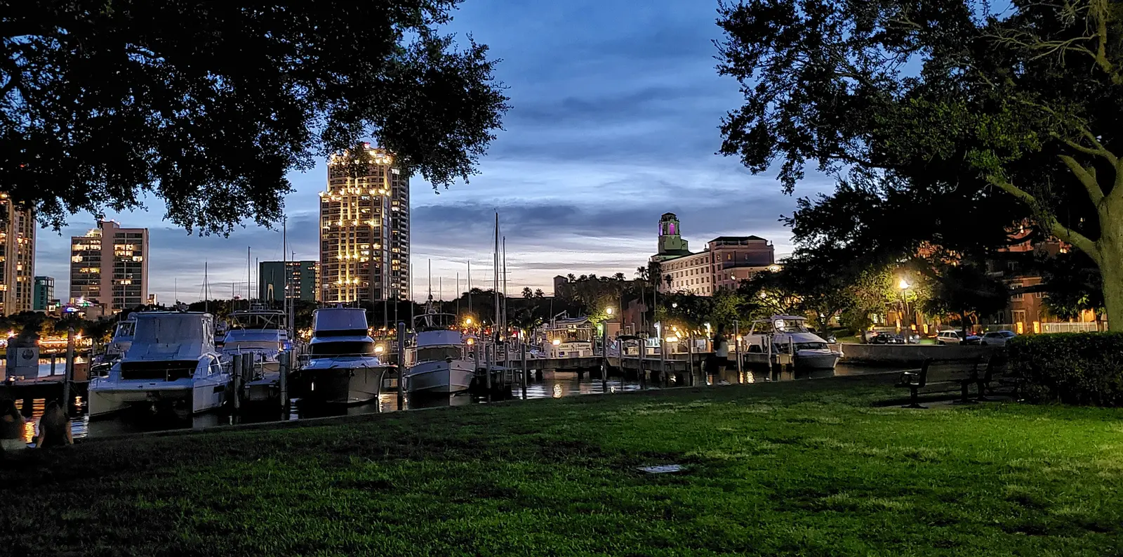 The lawn of Vinoy Park at dusk, with boats in the Vinoy Yacht Basin and the Vinoy hotel tower behind, in downtown St. Petersburg.
