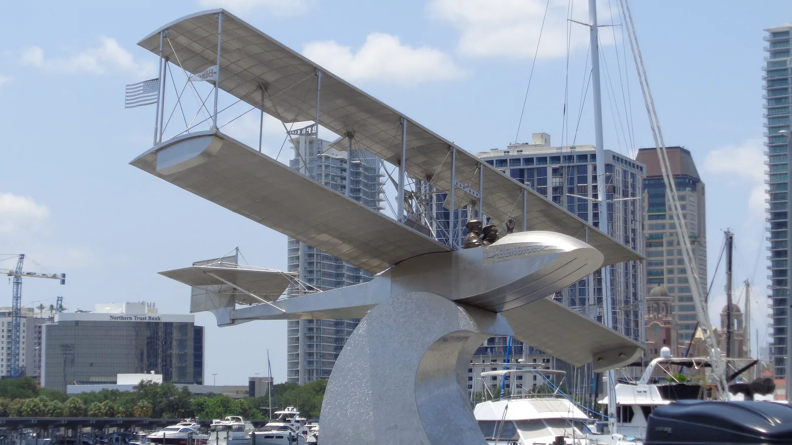 The World's First Airline Monument, a sculpture of the Benoist XIV airboat, beside the marina on the St. Pete Pier with downtown towers behind.