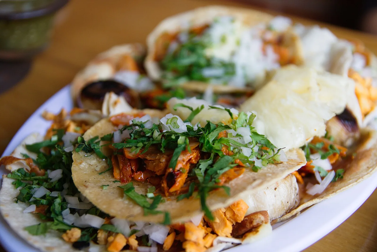 A plate of tacos al pastor topped with onion and cilantro. The photo was not taken at a place on this list.