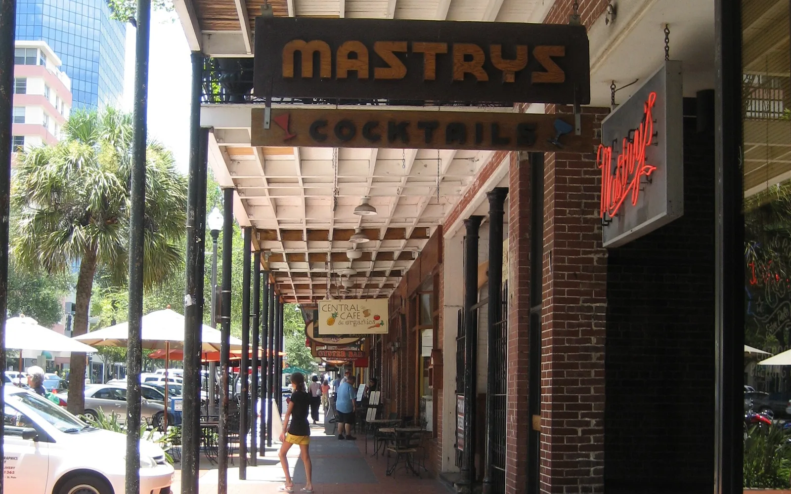 A covered sidewalk lined with bars and shops along Central Avenue in downtown St. Petersburg.