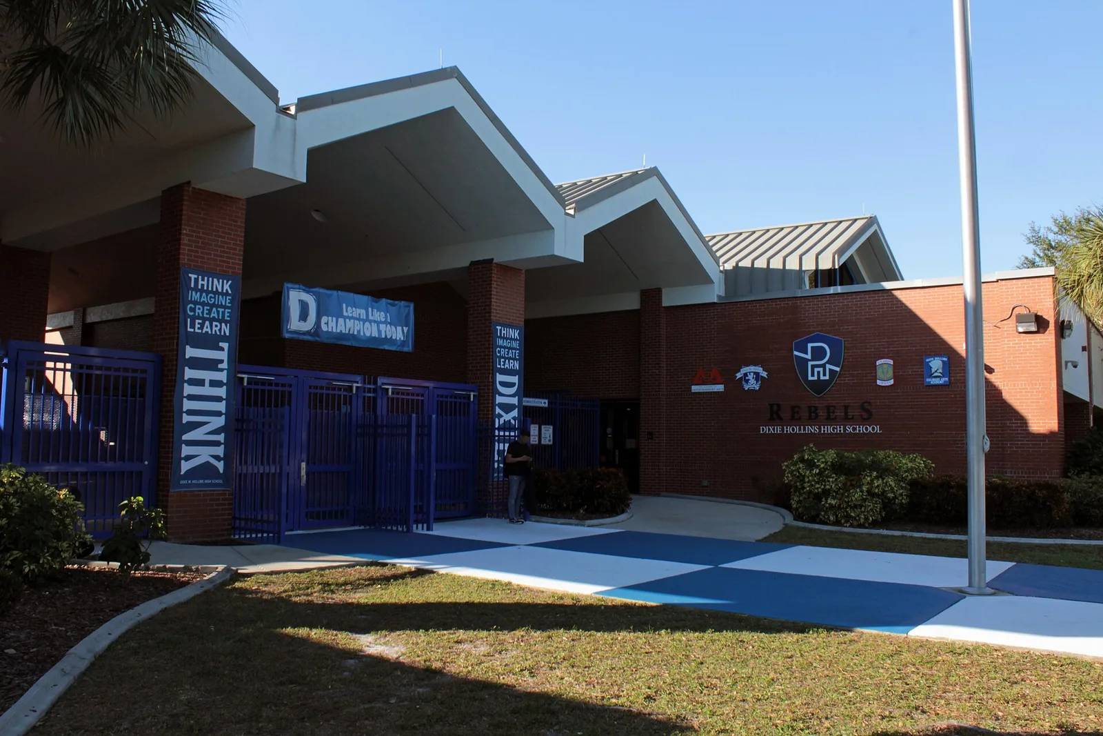 The gated main entrance of Dixie Hollins High School on 62nd Street North, with the Rebels sign on the wall.