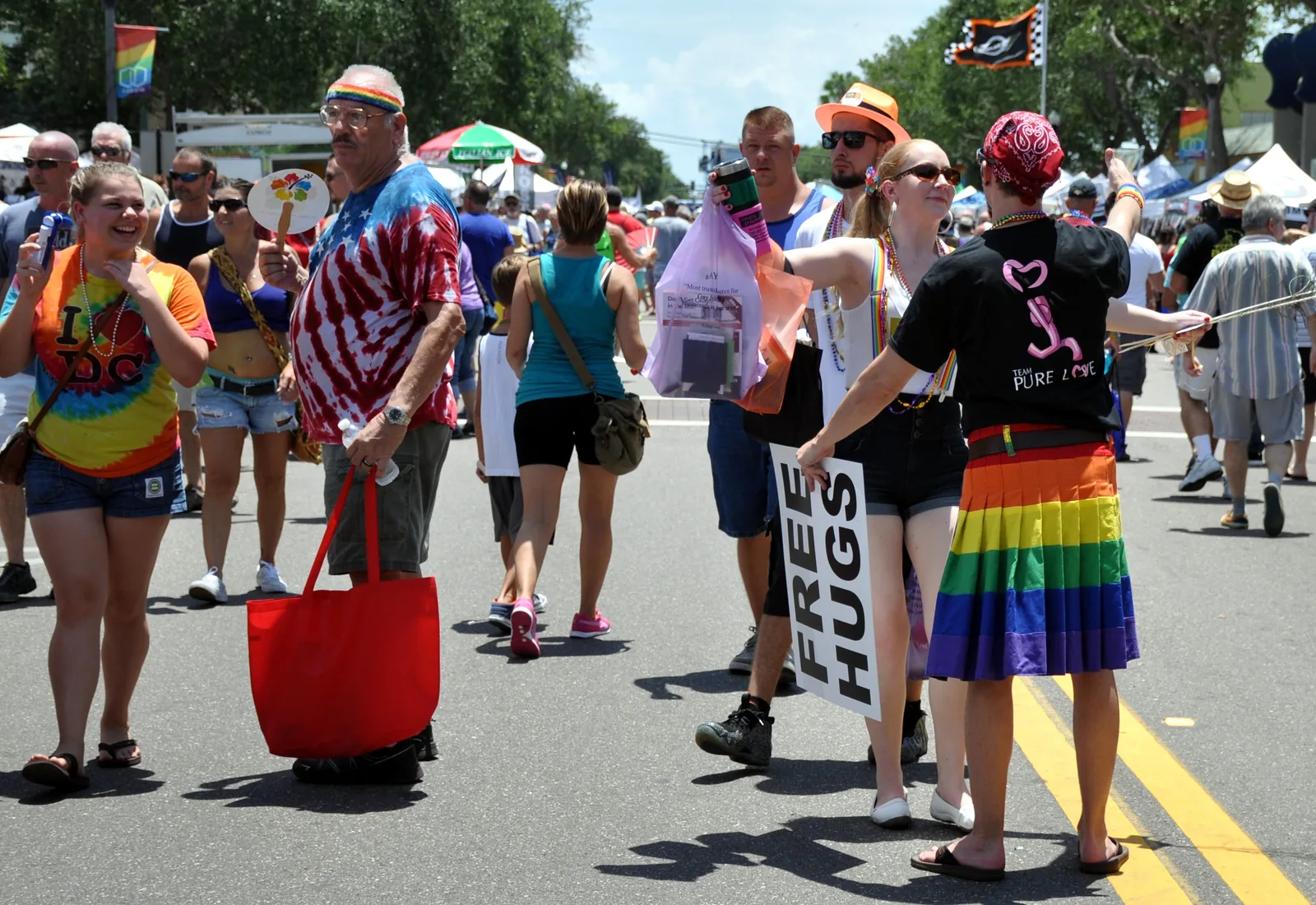 Festivalgoers, one holding a Free Hugs sign, on the street at the St. Pete Pride festival on Central Avenue in St. Petersburg.